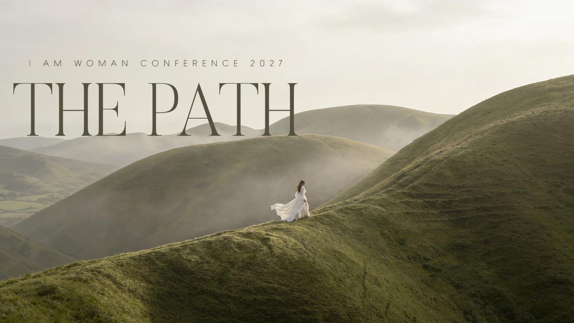 I Am Woman Conference 2027 — The Path. A woman in a white dress walks a misty green hillside.